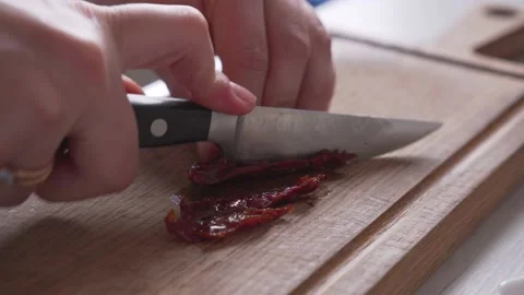 Slicing dried tomatoes on cutting board with knife Video stock 231720396