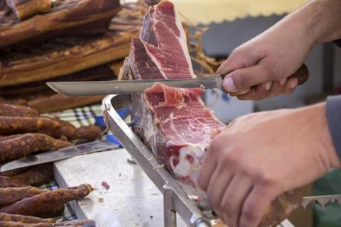 Slicing dry-cured ham prosciutto on the street market Stock Photos