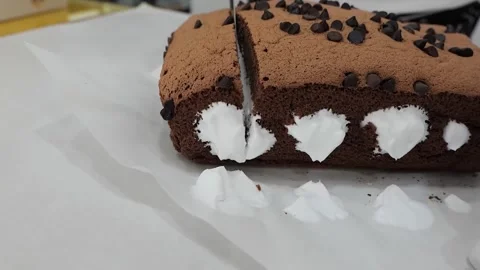 Slicing a Fluffy Chocolate Castella Cake with Cream Filling and Chocolate Chips Stock Footage 331780342