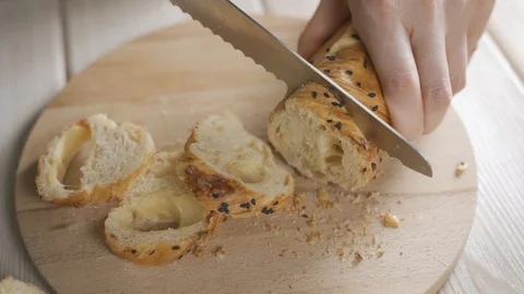 Slicing french bread by bread knife on wooden cutting board in kitchen Stock-Footage 123208457