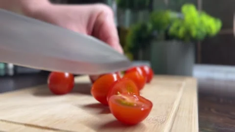 Slicing fresh cherry tomatoes with a large knife on cutting board Stock Footage 310503405