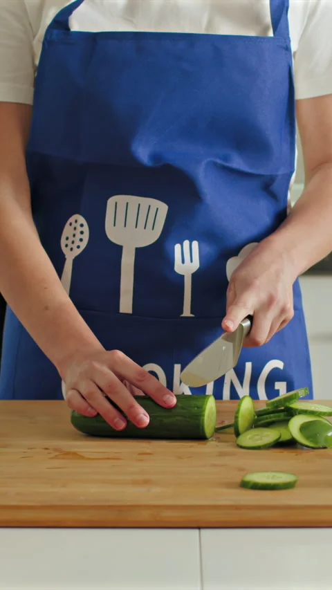 Slicing fresh cucumbers in a cozy kitchen setting for delicious meals Stock Footage 341762415