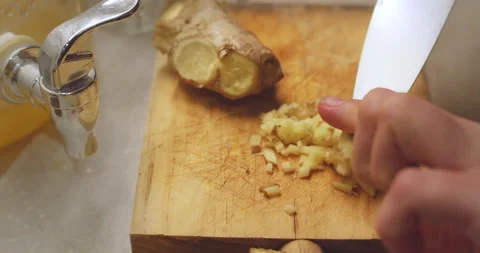 Slicing fresh ginger root on a wood cutting board. Raw spicy root used for Stock Footage 143255941