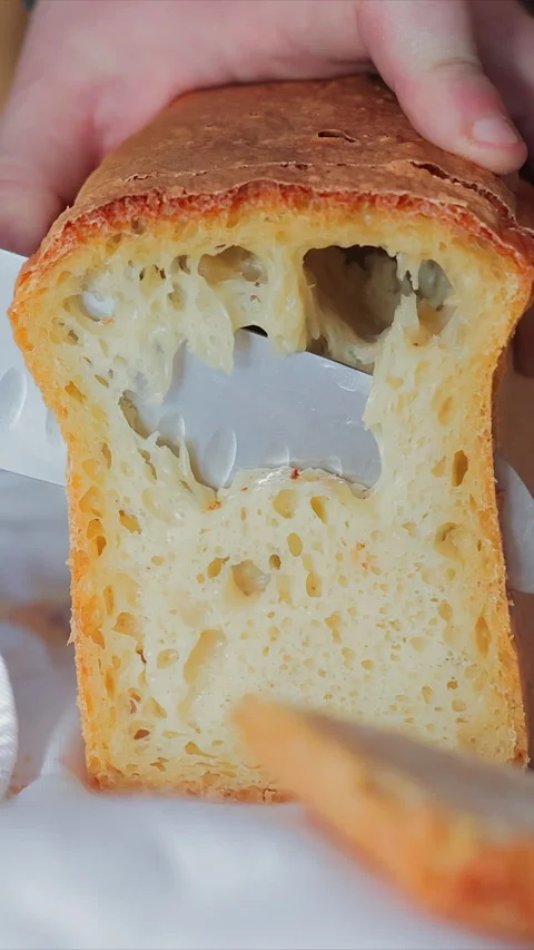 Slicing fresh homemade bread, soft airy texture with a golden crispy crust Stock Footage 307587900