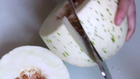 Slicing up fresh honey globe melon, showing seeds inside Stock Footage 174737557