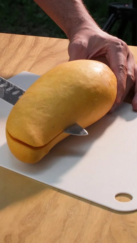 Slicing fresh mango on cutting board. Outdoor cooking tropical fruits. Vertical Stock Footage 314000883