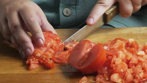 Slicing fresh red tomatoes with a knife on a cutting board on a wooden tabl.. Video stock 345089313
