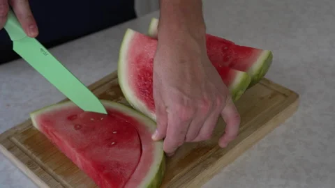 Slicing fresh red watermelon wedge with green knife Stock Footage 338120187