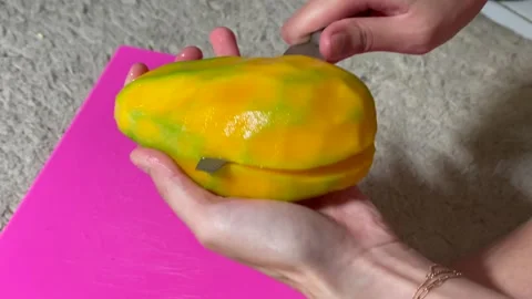 Slicing a fresh ripe mango fruit with a knife on a pink cutting board Stock Footage 327233960