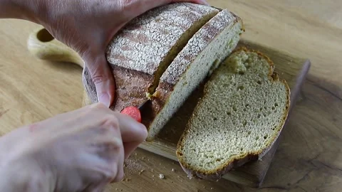 Slicing fresh rye bread on a wooden board Stock Footage 335792836