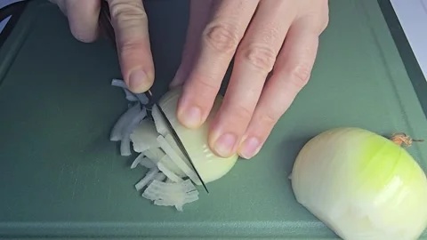 Slicing a fresh white onion into half-rings on a cutting board in the kitchen Stock Footage 341676814