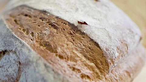 Slicing a Freshly Baked Artisan Bread Loaf on a Wooden Cutting Board for Stock Footage 295515376