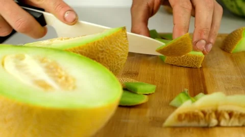 Slicing Galia melon into chunks, using a ceramic knife, on a bamboo Stock Footage 134726261