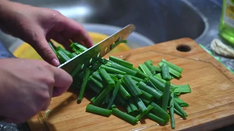 Slicing Green Onion into Small Pieces on a Cutting Board Stock Footage 346487624