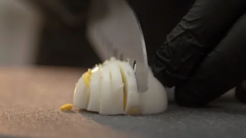 Slicing half boiled egg on cutting board in latex gloves Stockbeeldmateriaal 121364340