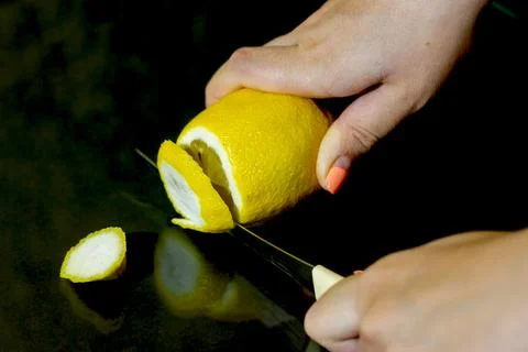 Slicing lemon on black background Stock Photos