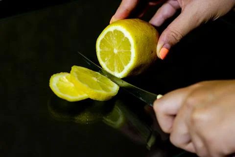 Slicing lemon on black background Photos