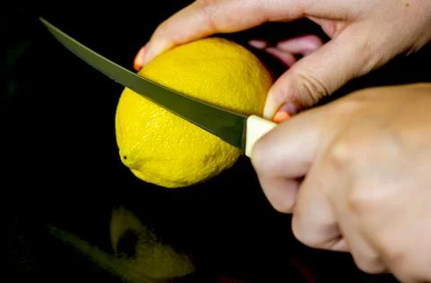 Slicing lemon on black background Stock Photos