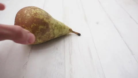Slicing pear with a kitchen knife on a white wooden background Vídeo Stock 130518567