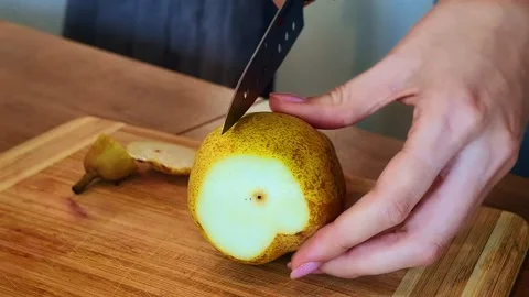Slicing a pear into thin pieces with a kitchen knife on a cutting board. Stock Footage 337257319