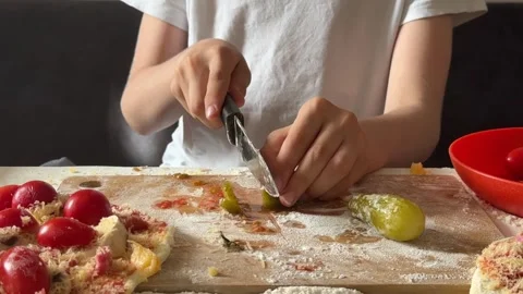 Slicing pickles for homemade pizza, unrecognizable child’s hands, part of Stock Footage 337339079