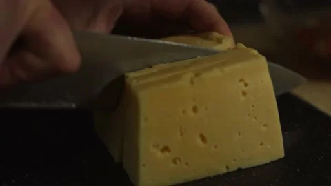 Slicing a piece of cheese on a cutting board. Preparing salad of crab sticks Stock Footage 150235338
