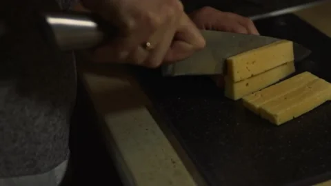Slicing a piece of cheese on a cutting board. Preparing salad of crab sticks Stock Footage 150235518