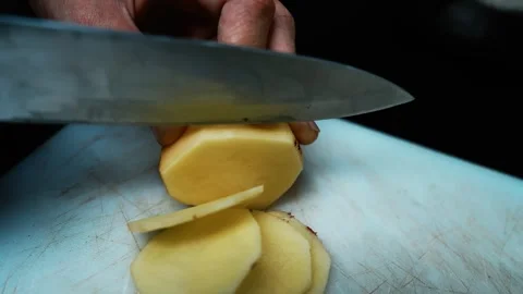 Slicing a Potato on Cutting Board, Close-up of hands slicing a peeled potat.. Stock Footage 304978595