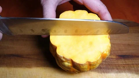 Slicing a pumpkin with a knife on the kitchen table Stock Footage 168652613
