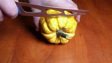 Slicing a pumpkin with a knife on the kitchen table Stock Footage 168652699