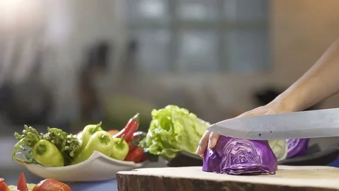 Slicing purple cabbage with kitchen knife on wooden board, close up, uhd 4k. Stock Footage 77640599