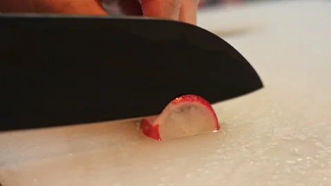 SLICING RADISH WITH A BLADE ON A KITCHEN BOARD, EXTREME CLOSE UP. Stock Footage 128604446