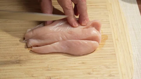 Slicing Raw Chicken Breast Into Long Strips on a Cutting Board Stock Footage 341775419