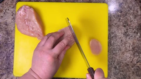 Slicing raw chicken breast using a cleaver on a cutting board. Stock Footage 301328765