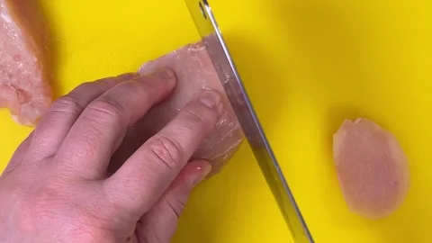 Slicing raw chicken breast using a cleaver on a cutting board. Top view. Video stock 301884386
