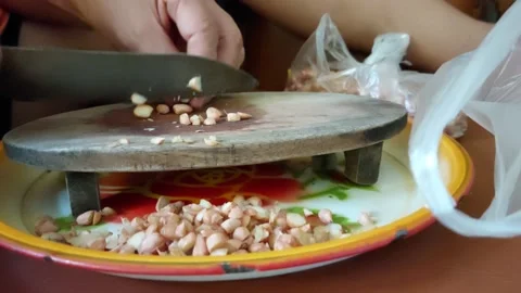 Slicing raw peanuts using a knife and a wooden cutting board Vidéo 231455202