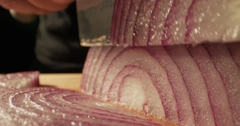 Slicing red onion with a large knife or axe on a cutting board. Making vegetable Stock Footage 294482028