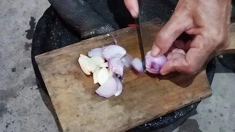 Slicing red onions with a small knife made in the Buleleng region Stock Footage 219214746