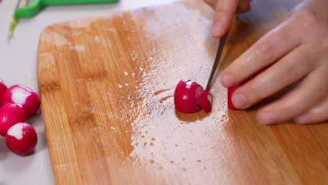 Slicing a red radish into thin rounds for a spring detox salad Vídeos de archivo 346800295