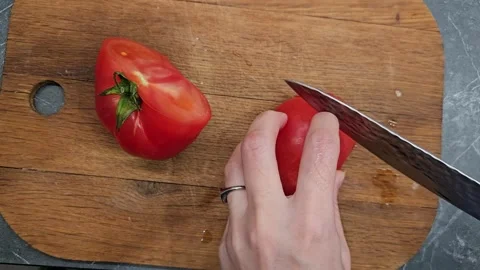 Slicing ripe tomato with precision in cozy kitchen setting Stock Footage 336202988