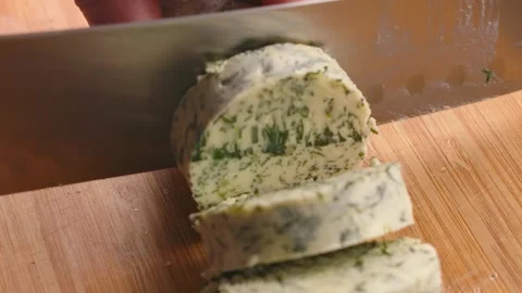 Slicing a round of fresh garlic herb compound butter Stock Footage 314045930