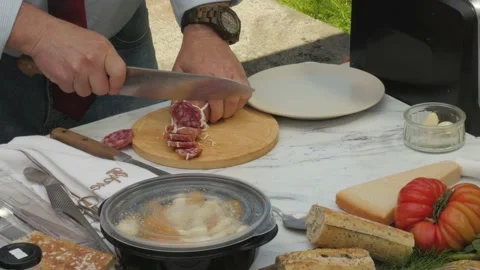 Slicing salami on patio table. Видео 155426916