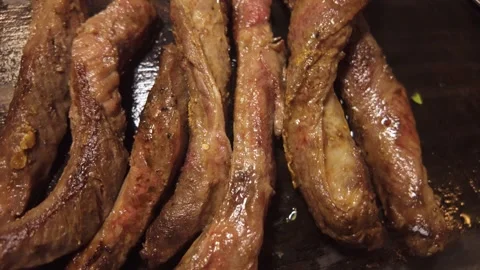 Slicing Seared Beef Strips into Pieces on a Wooden Cutting Board Stock Footage 344670041