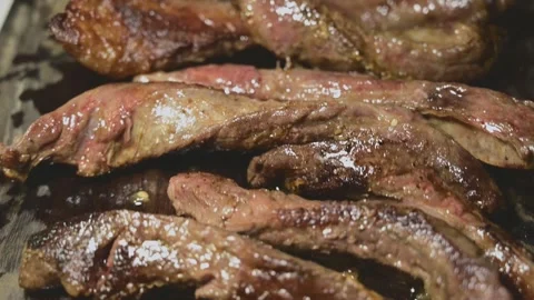 Slicing Seared Beef Strips into Pieces on a Wooden Cutting Board Stock Footage 344670449