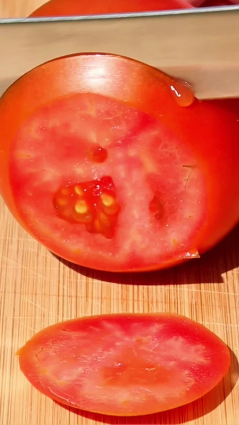 Slicing tomato into round pieces on wooden cutting board Video stock 316932053