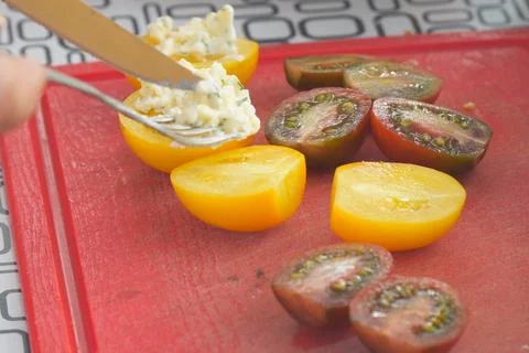 Slicing Tomatoes and Adding Cheese on Cutting Board Foto stock