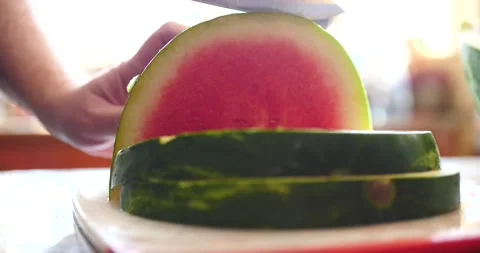 Slicing up watermelon on white cutting board during the day in a kitchen Stock Footage 205330204