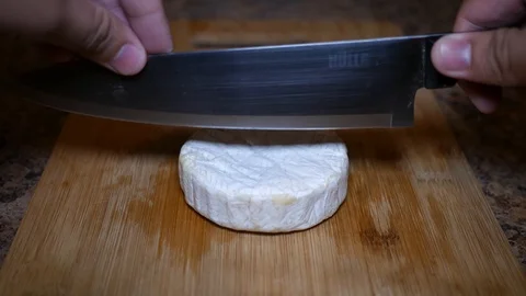 Slicing a Wheel of Cheese With a Knife Stock Footage