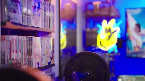 Slide and pan over gaming room with Japanese manga comics shelf in focus 4K Vídeos de archivo 301504891