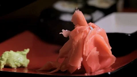 A slide of ginger on a red plate, pouring soy sauce in the background Stock Footage 92441391
